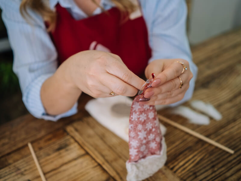 A person in a red apron making DIY Christmas crafts